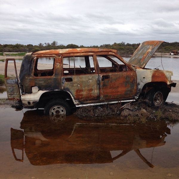 Old rusty car stuck in muddy water.
