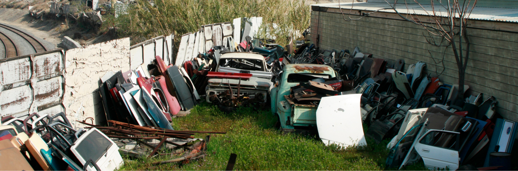 Several old cars and car parts in a junkyard