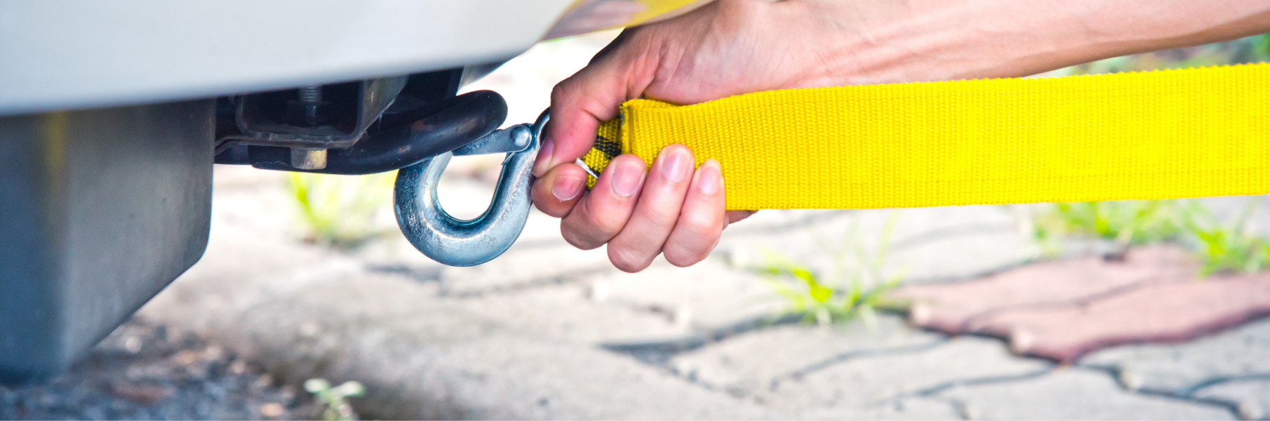 Yellow strap being hooked up to a white car